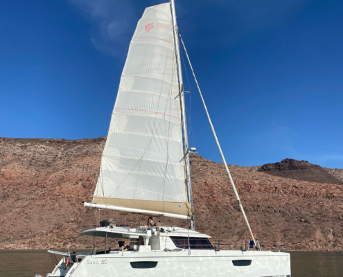 Mainsail and headsail set with desert coastline in view.