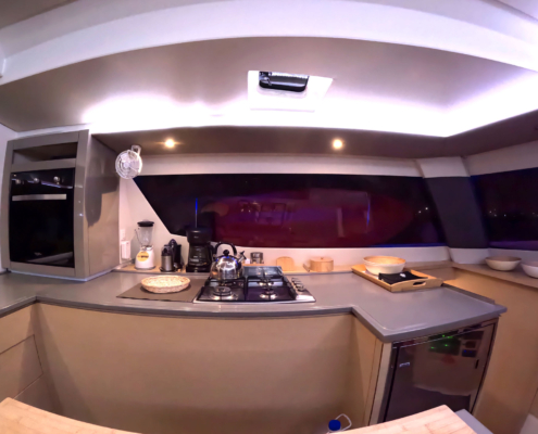 Galley kitchen with appliances and serving counter at night.